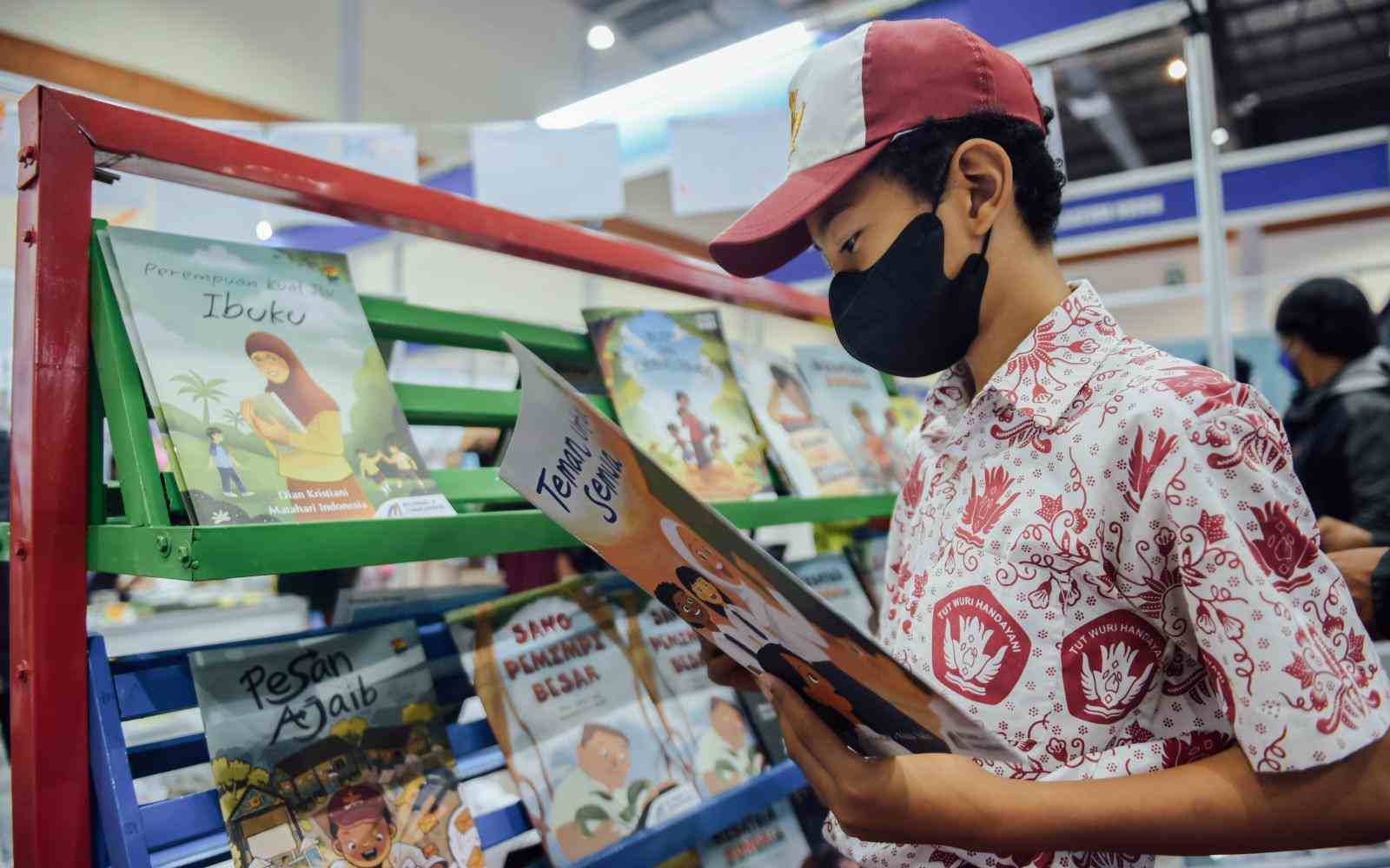 An Indonesian boy reads one of the children's books in front of the shelf displaying the "Becoming a Changemaker" series at the Indonesian International Book Fair