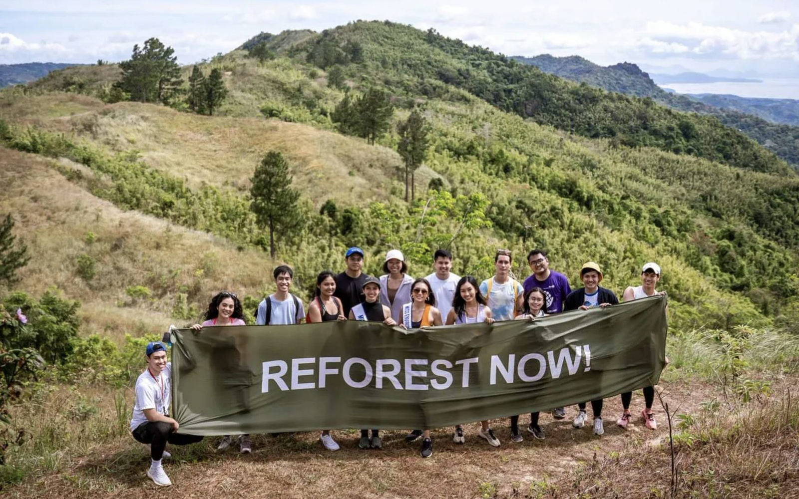 Group shot of Masungi Staff. They are holding a banner that says "Reforest Now". 