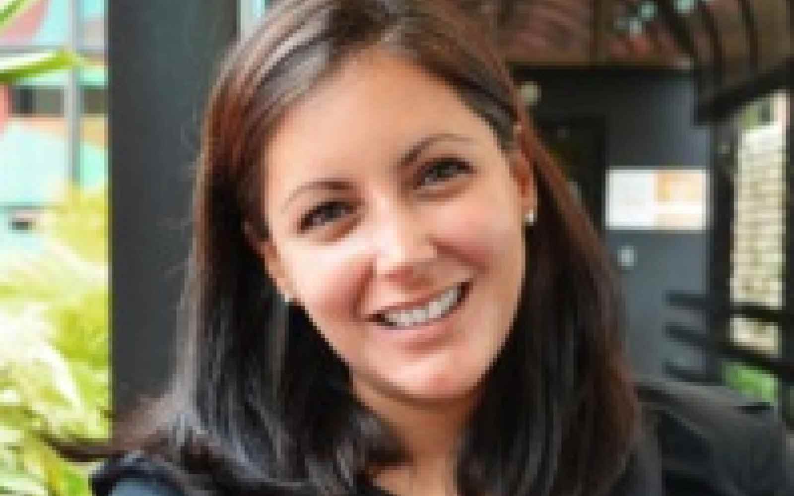 Photo of Lorena Garcia Duran, Director of DEI initiatives at Ashoka. Person with lighter skin and dark brown shoulder length hair smiling at the camera. Background of a covered walkway