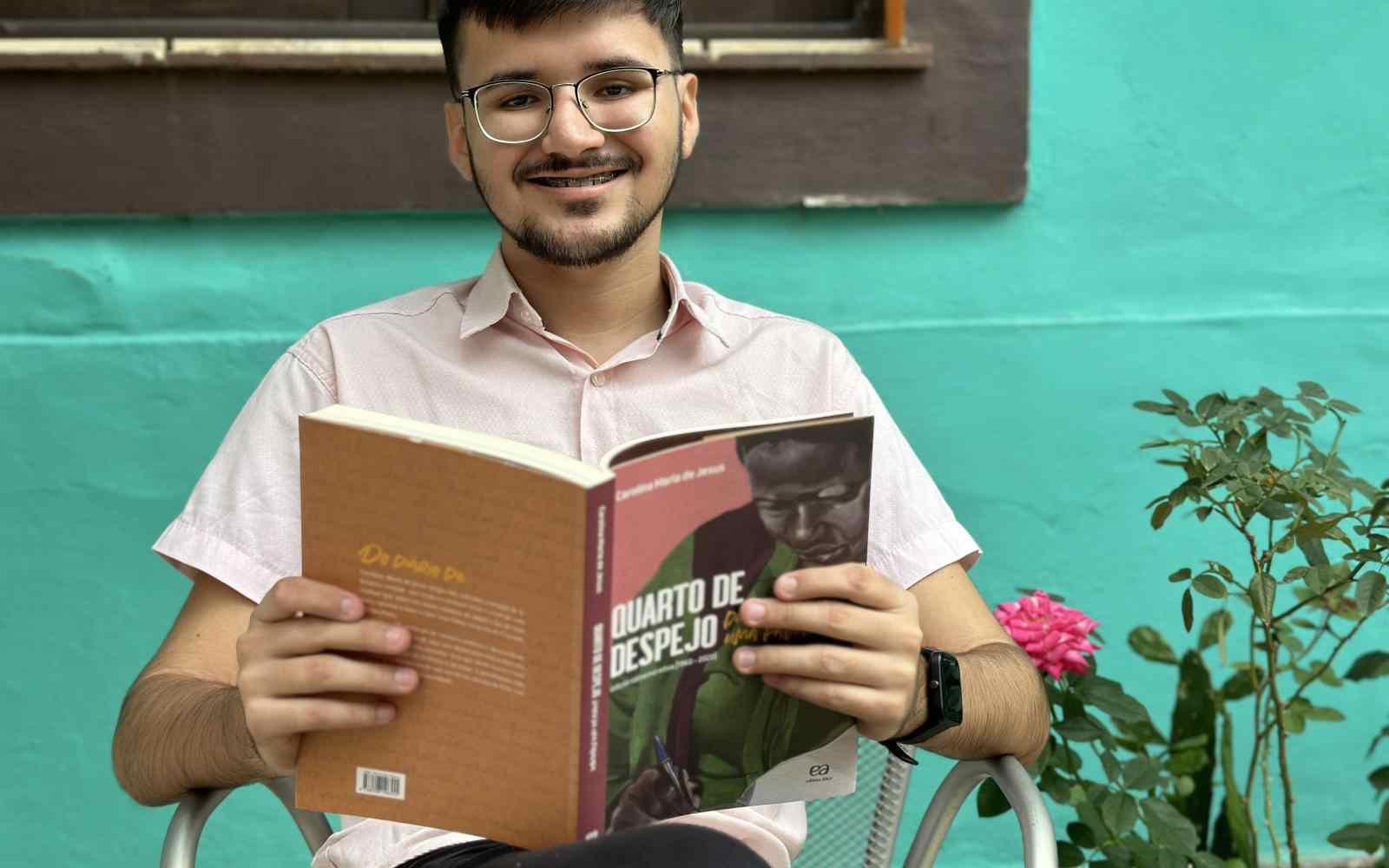 Jovem Transformador Ashoka Raislúcio (Garoto branco de cabelos curtos, lisos e castanhos usando óculos) segurando exemplar do livro Quarto de Despejo