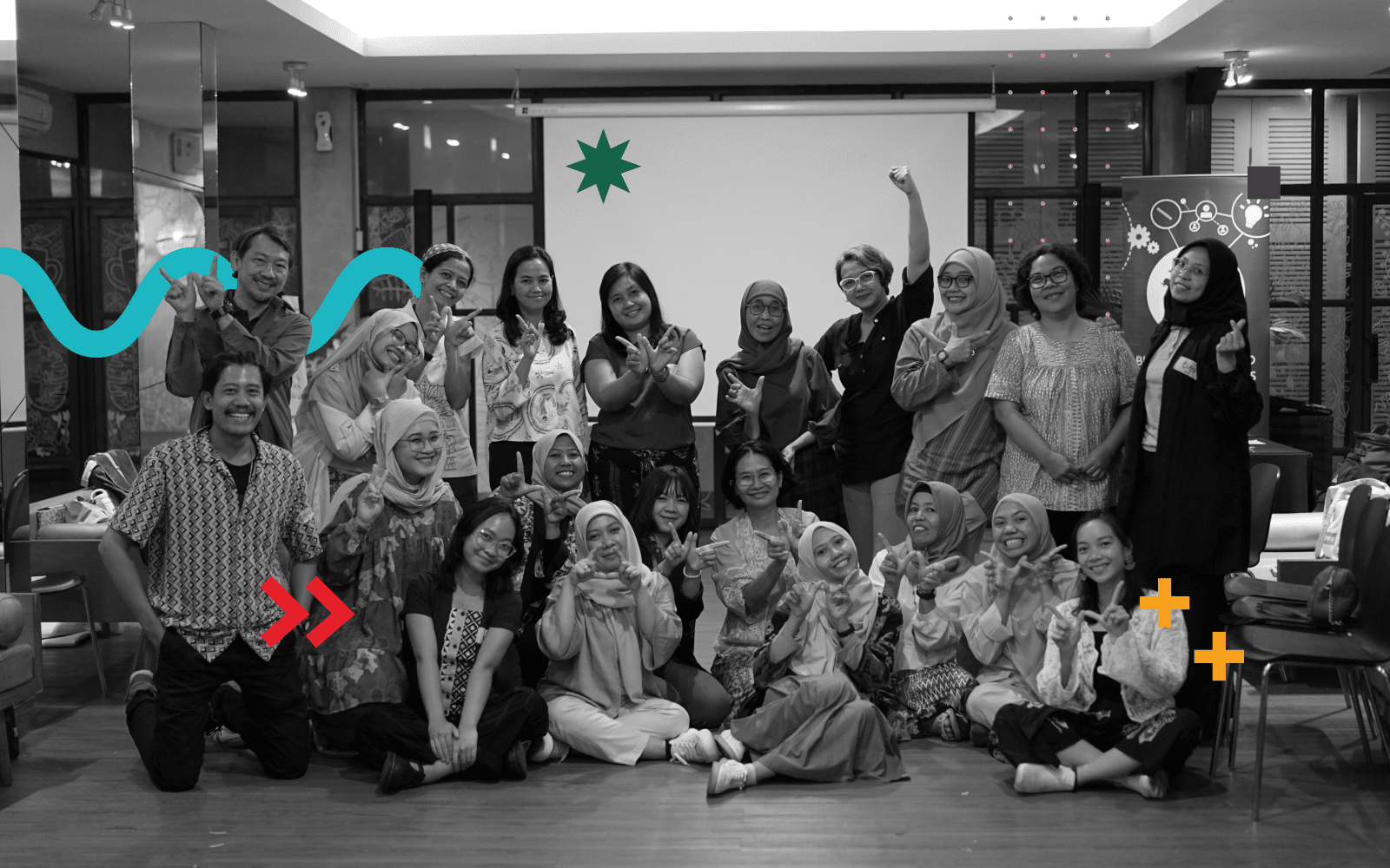 A very diverse group of people making the letter "W" with their hands. Graphic elements have been added to the image, such as a light blue curved zig-zag, two red arrows, two orange plus signs, a green 8-pointed star, a purple square and several pink dots.