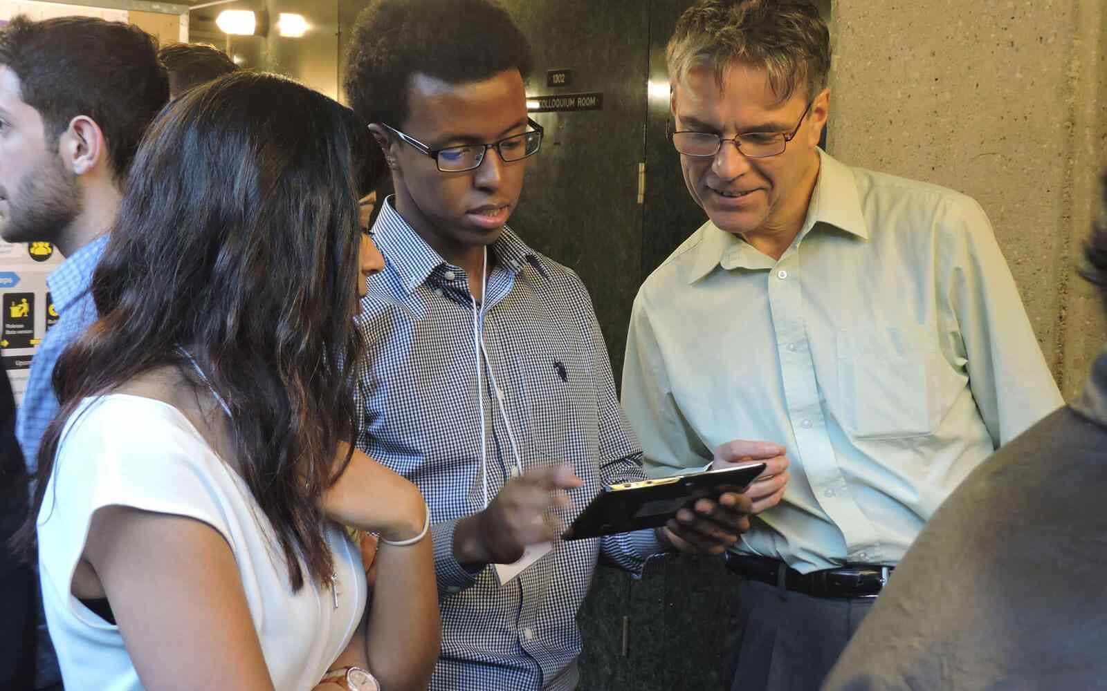 Brett Matthews looking at an ipad with two other people in a conference room