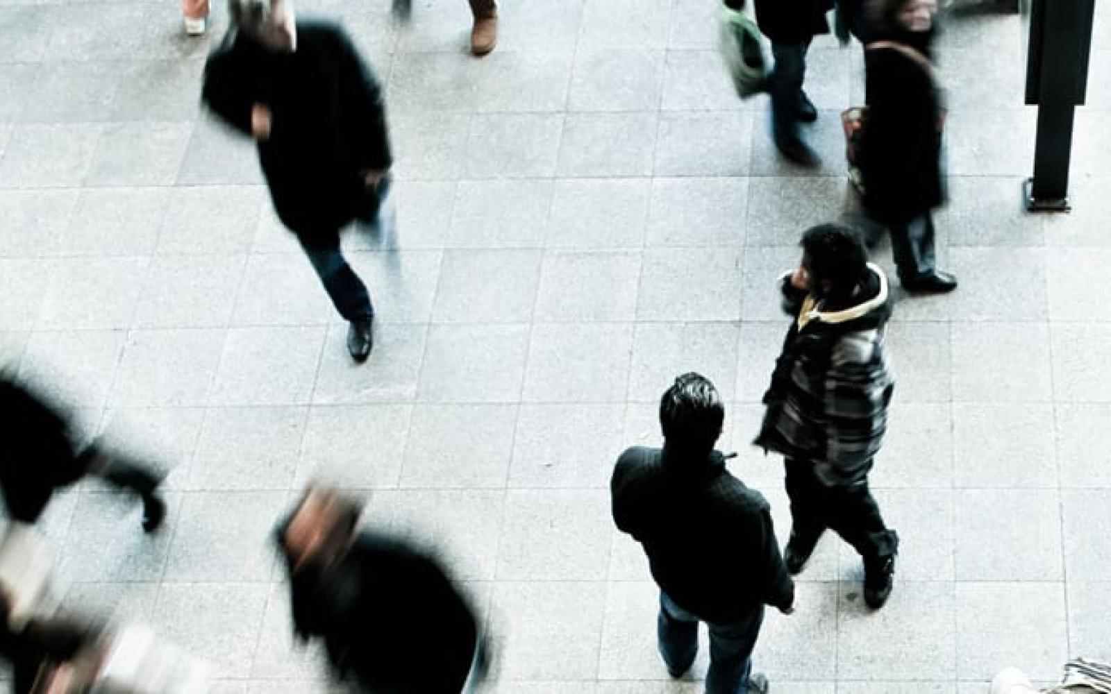 People walking on a white / grey sidewalk dressed in winter clothes. photo taken from about 20-30 feet above them