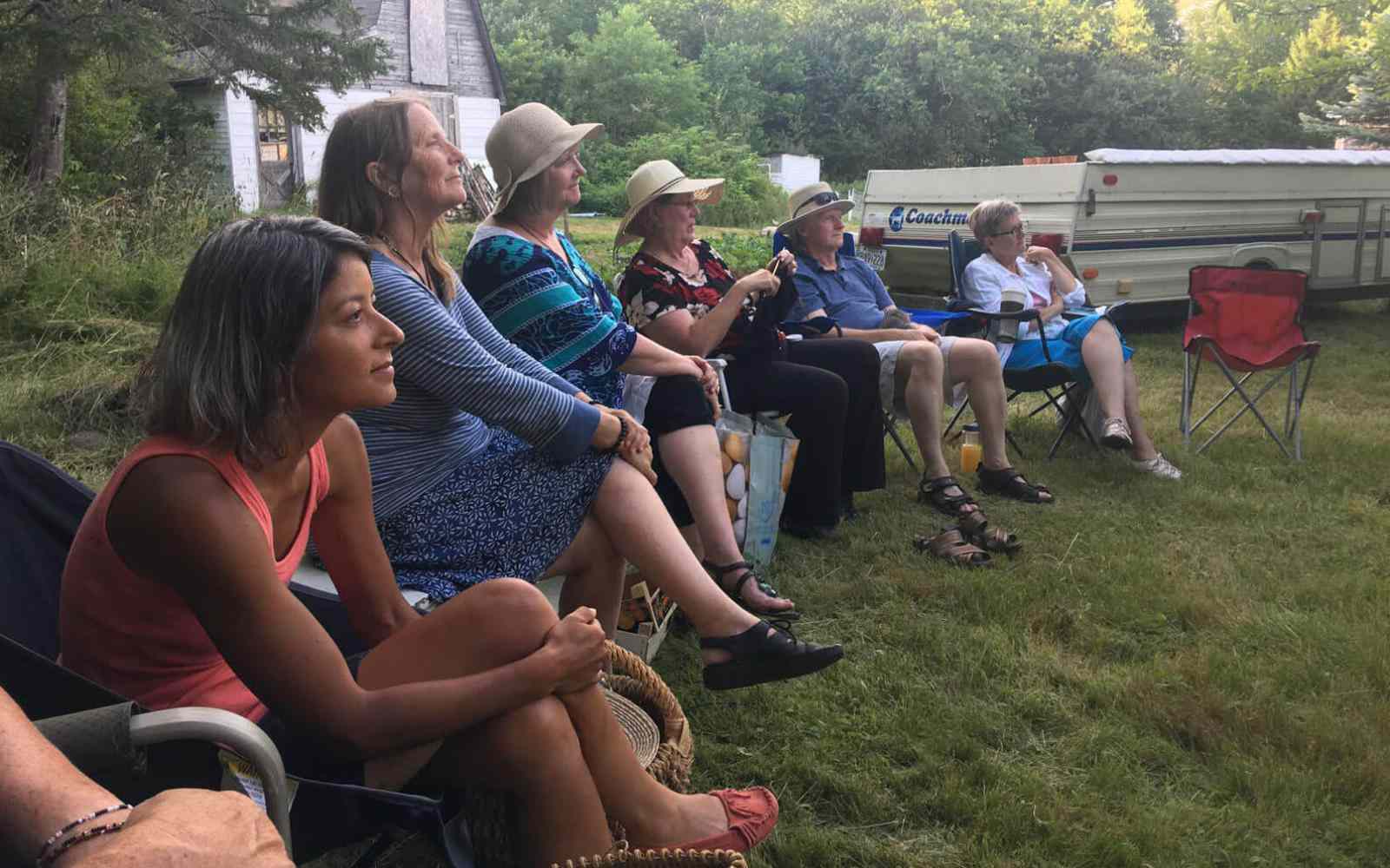 Group of people in a field paying attention to a Life.School.House session