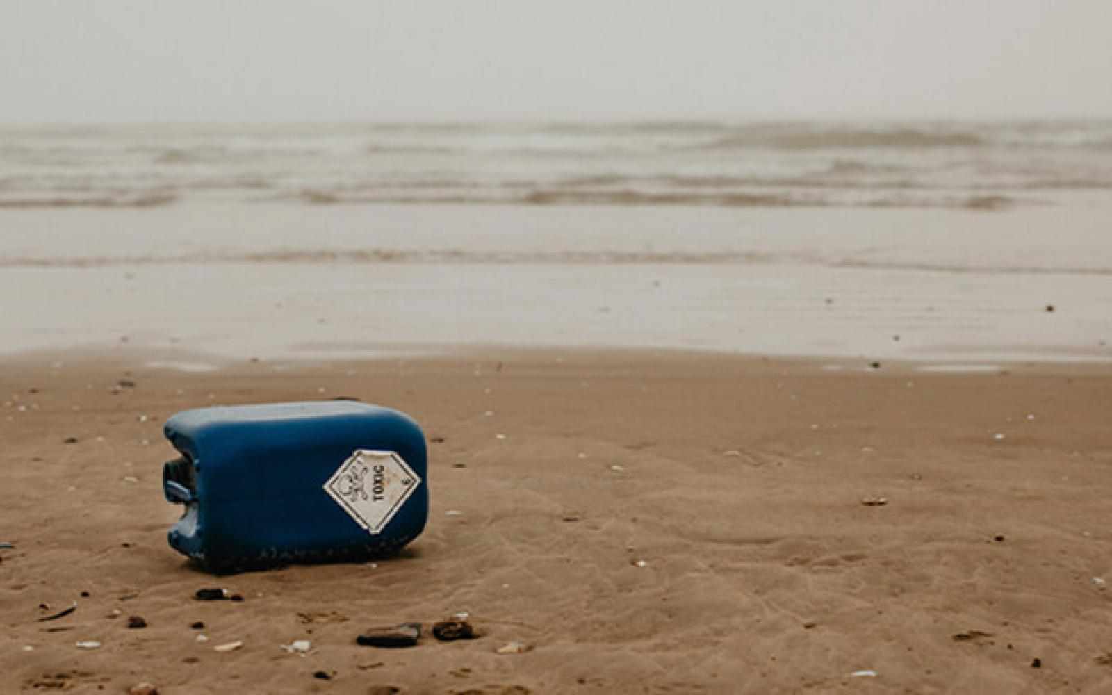 Image of a can of oil knocked over on a beach