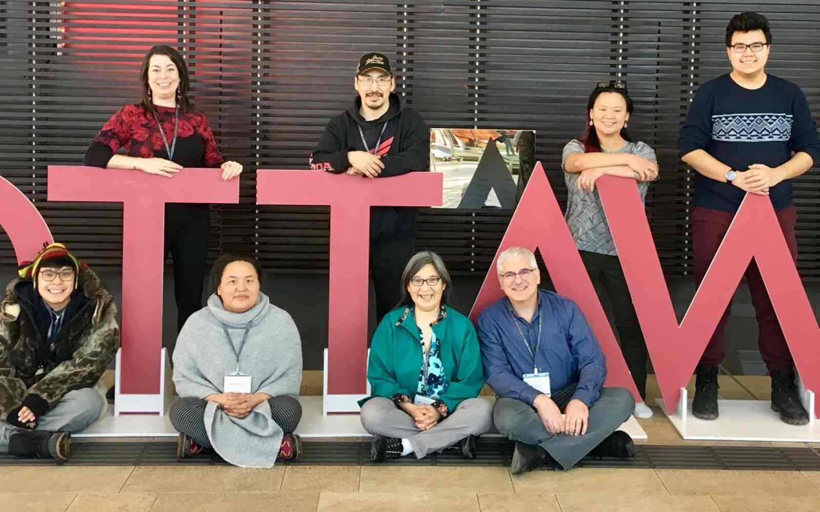 Group of youth posing with a giant OTTAWA sign in outlined 3D lettering