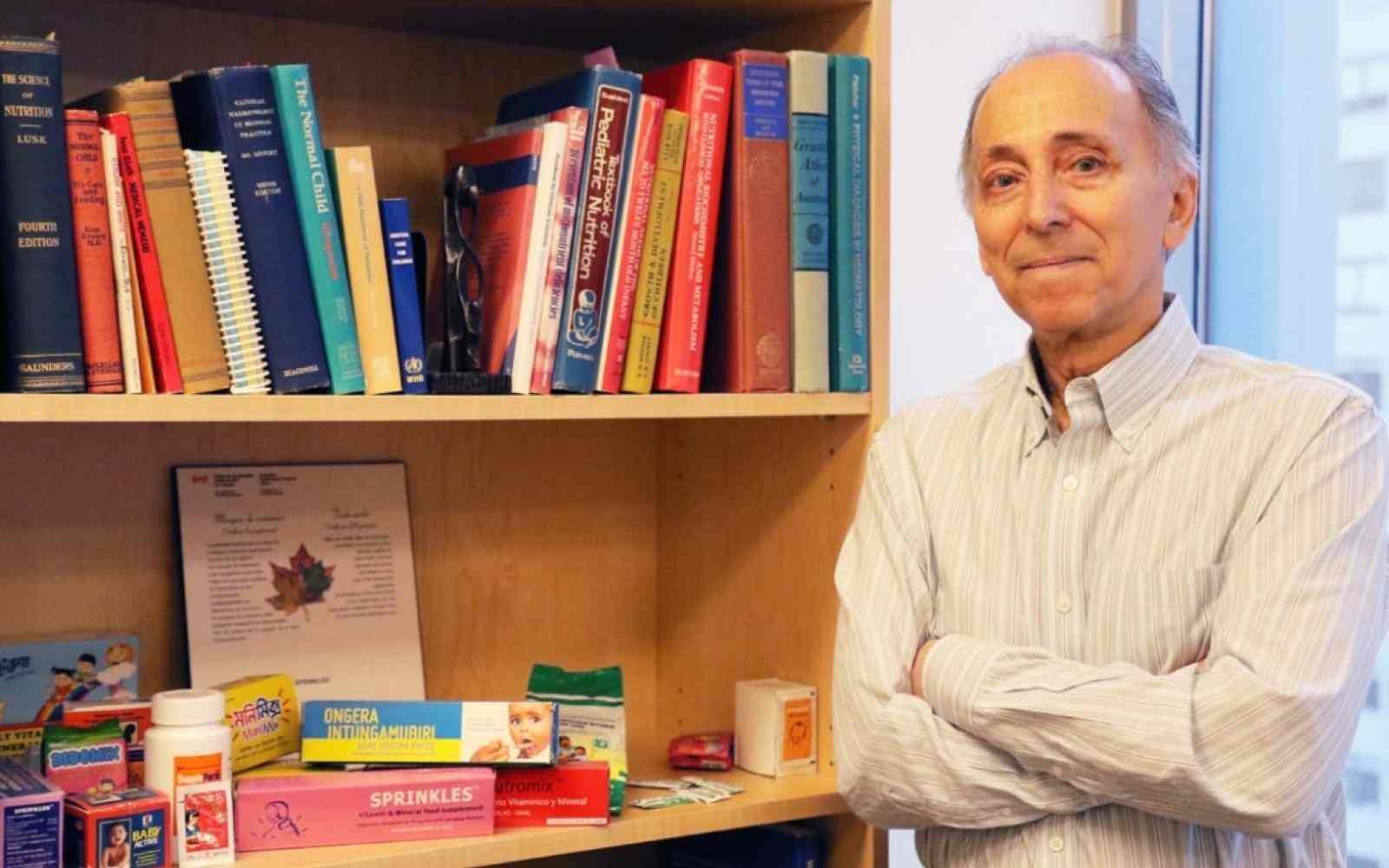 Photo of Canada Fellow Stanley Zlotkin next to a bookcase showcasing his nutrition and hunger fighting product Sprinkles