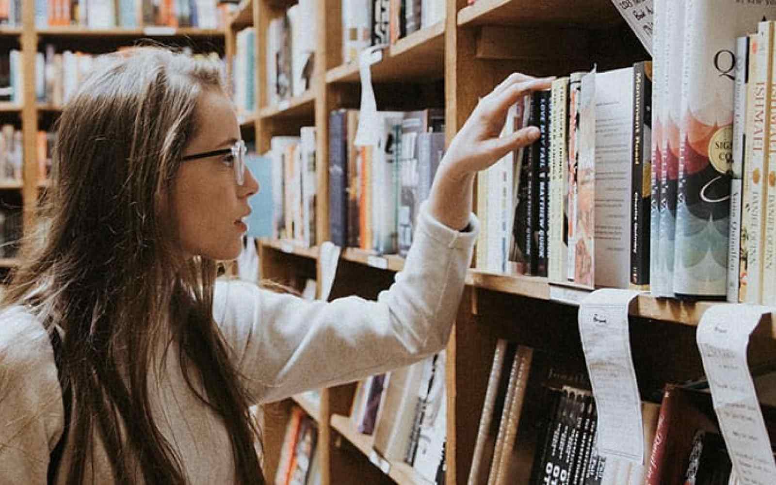 Photo of a young teen picking out a book in a bookstore or library
