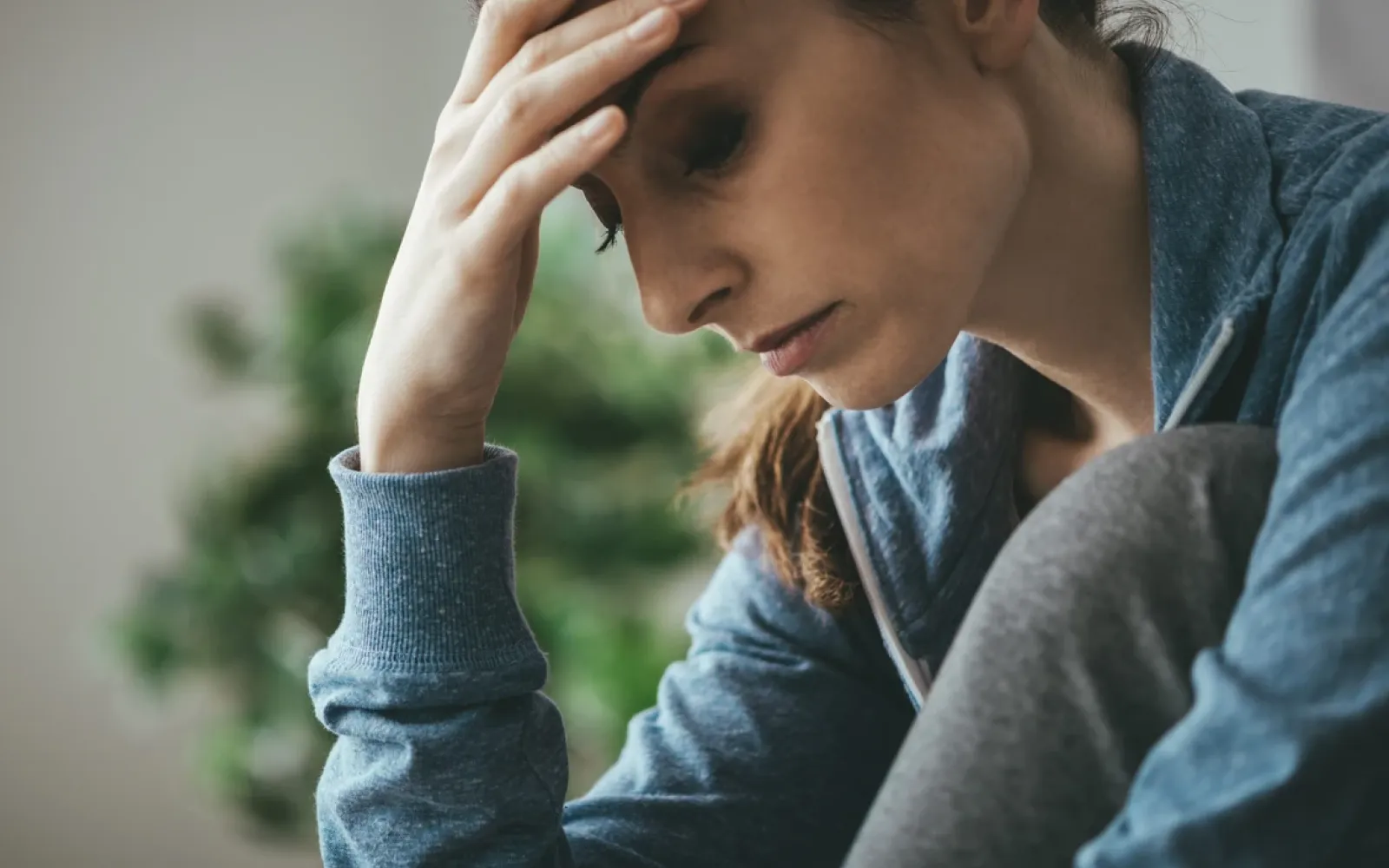 Photo of woman visibly stressed out looking down with hand on forehead