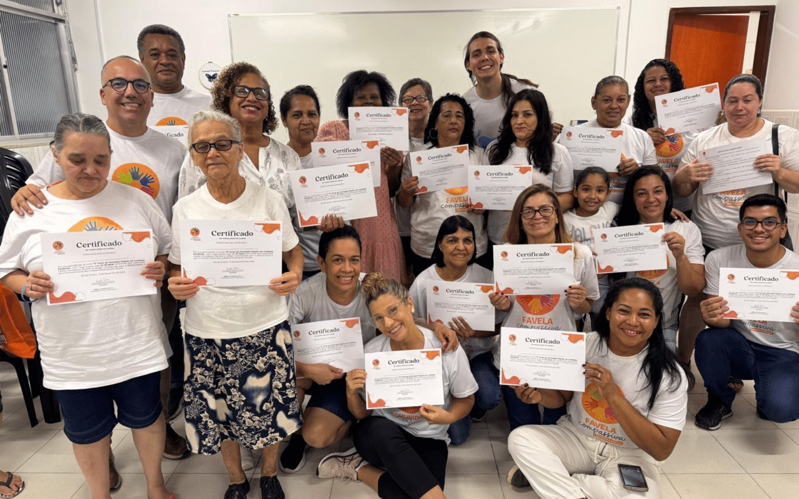 Grupo de pessoas reunidas em uma sala segurando certificados