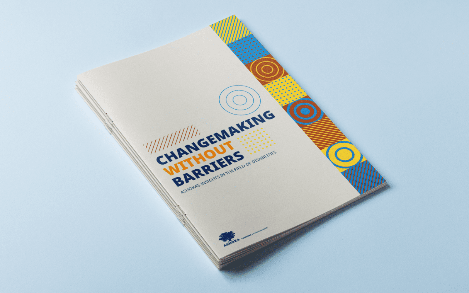 Stack of printed reports titled “Changemaking Without Barriers: Ashoka’s Insights in the Field of Disabilities,” placed on a light blue surface, with a beige cover and a vertical strip of colorful geometric patterns on the right side.