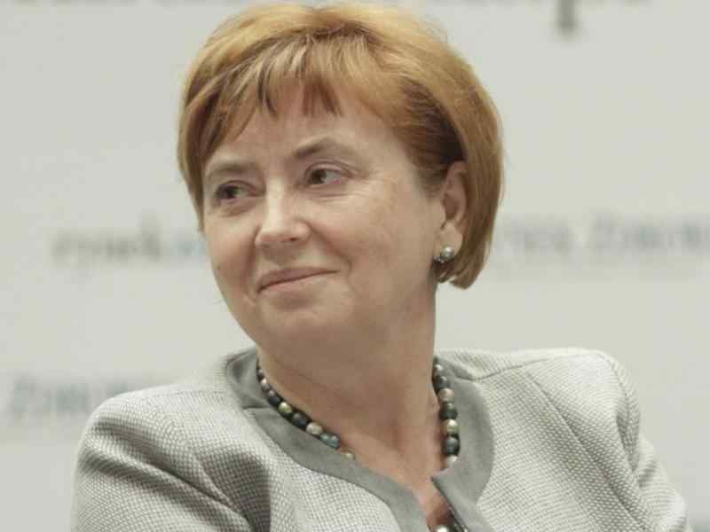 Zdjęcie uśmiechniętej Elżbiety Szwałkiewicz w szarej marynarce i niebieskim naszyjniku.