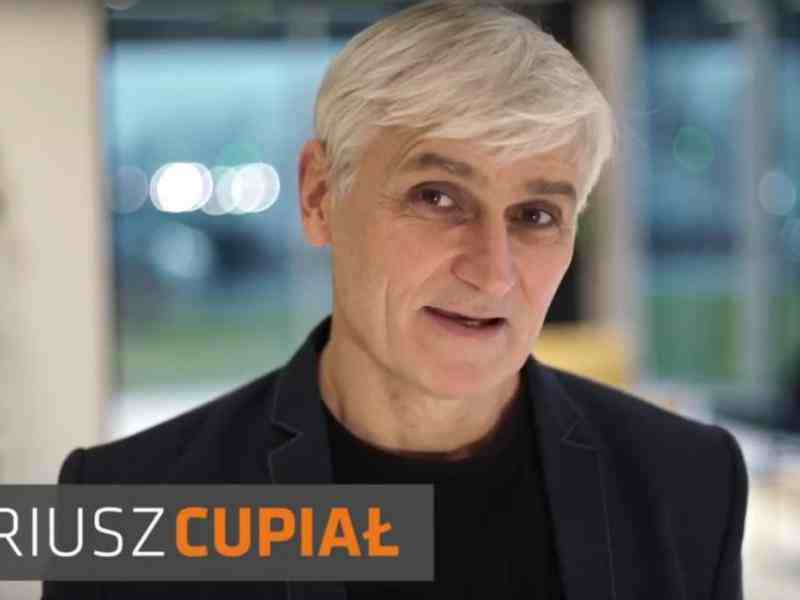 Zdjęcie uśmiechniętego Dariusza Cupiała. W lewym górnym rogu logo tato.net