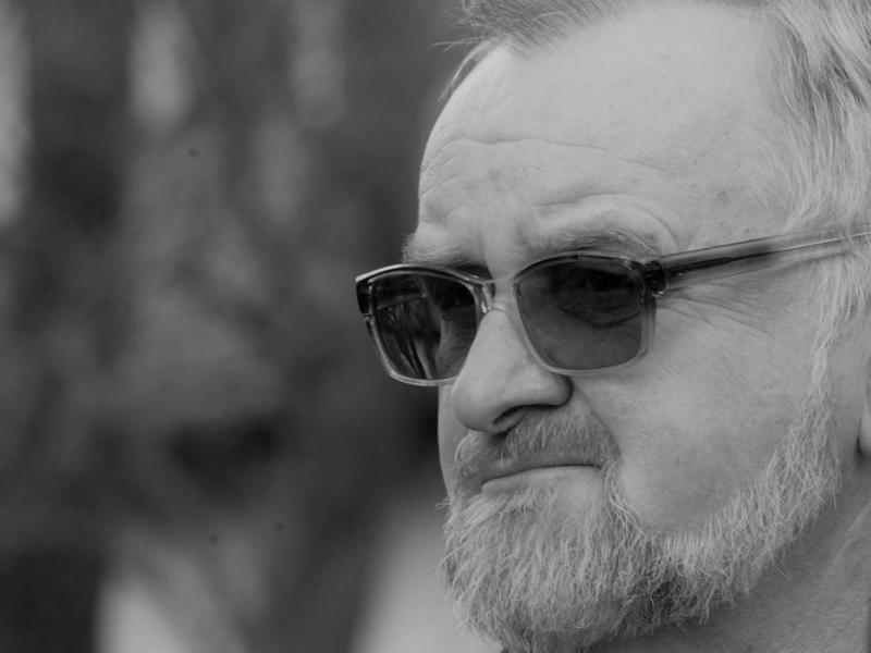 Czarno-biały portret Krzysztofa Liszcza w okularach przeciwsłonecznych.