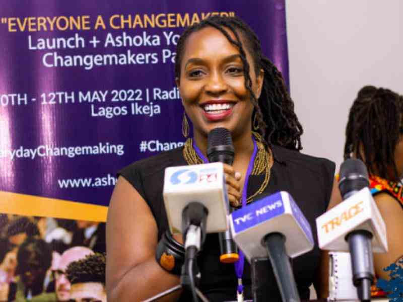 Angelou Ezeilo, Children and Empathy Leader of Ashoka Africa, is speaking in front of a number of microphones.