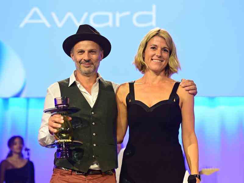 Fellow Jonas Staub posing with presenter and holding a trophy at award ceremony