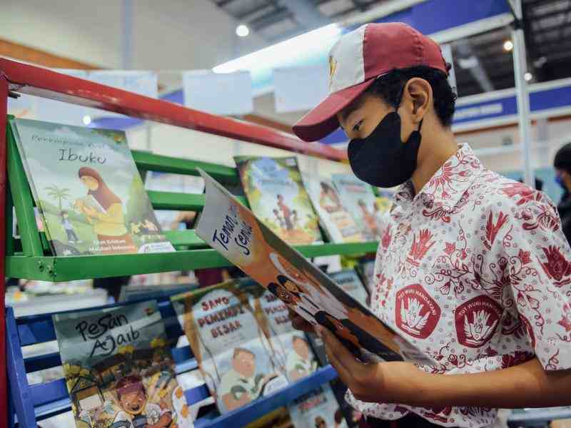 An Indonesian boy reads one of the children's books in front of the shelf displaying the "Becoming a Changemaker" series at the Indonesian International Book Fair