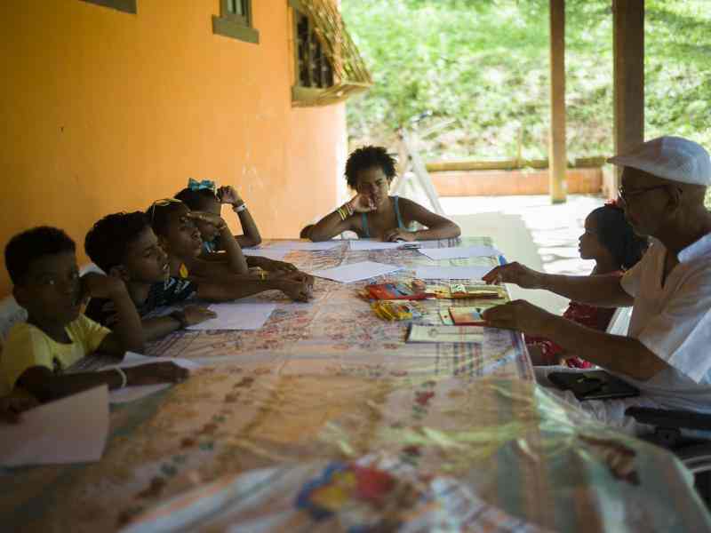 Kids and an older adult in a wheelchair seated around a table, about to do a writing prompt together