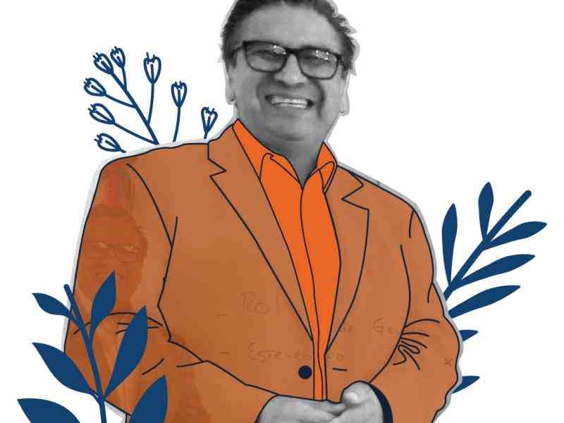 Se ve un hombre de lentes sonriendo. 