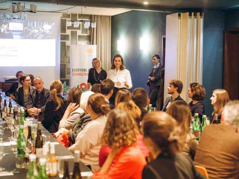 Photo of seated group looking back at the female speaker during the dinner reception