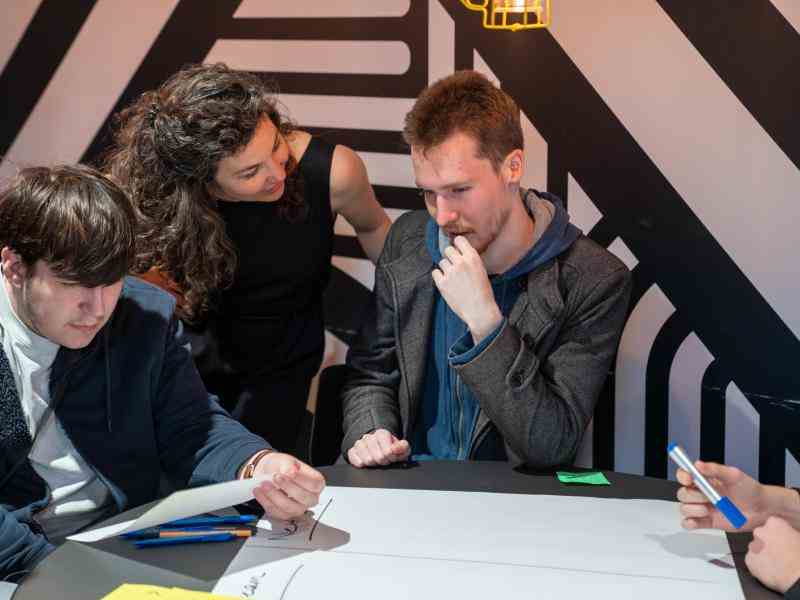 Photo of facilitators from Ashoka and a youth sitting at a table