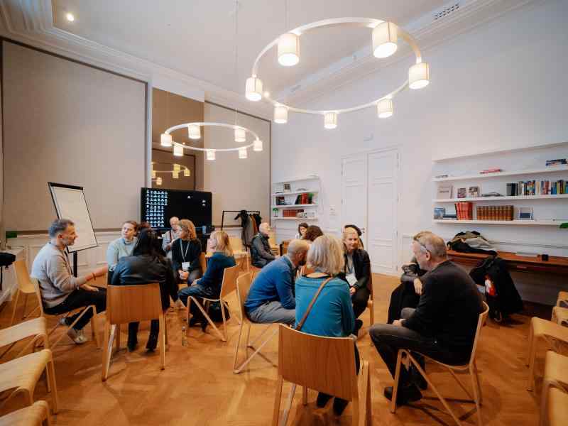 Photo of small groups of people sitting in a big room