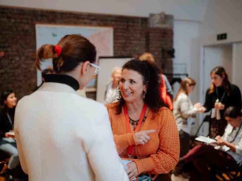 Photo of two women standing in conversation in a workshop room