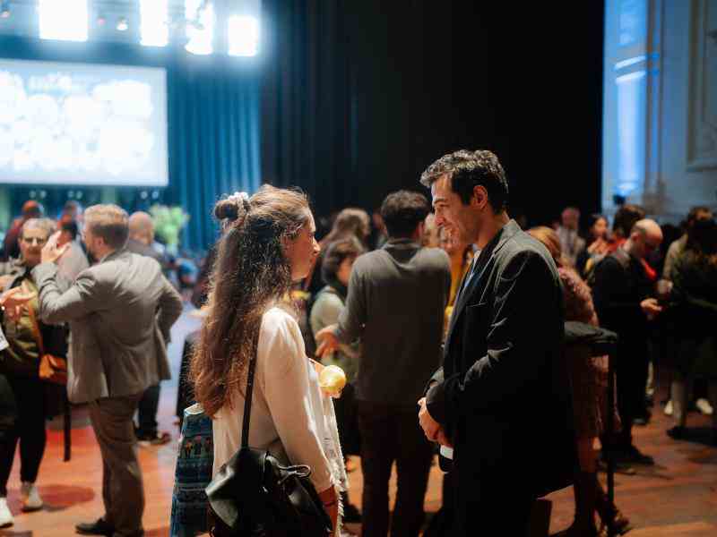 Photo of man and woman standing in conversation in a conference hall