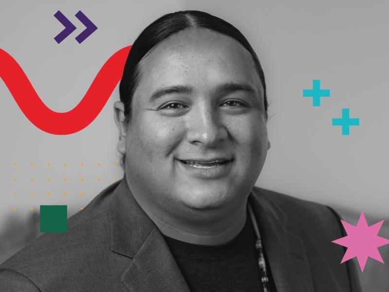 It is a black and white photo featuring an Indigenous man, wearing a t-shirt under a jacket. There are some graphic elements around him, as a red zigzag curved-line, two purple arrows, two blue plus sign, a small green square and a pink eight-pointed star.