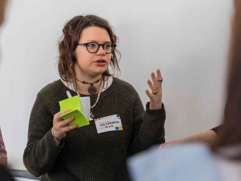 A girl holding post-its in one hand and talking