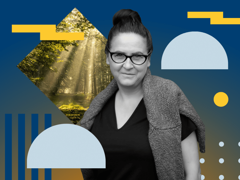 A woman wearing glasses and black shirt, forest in a background