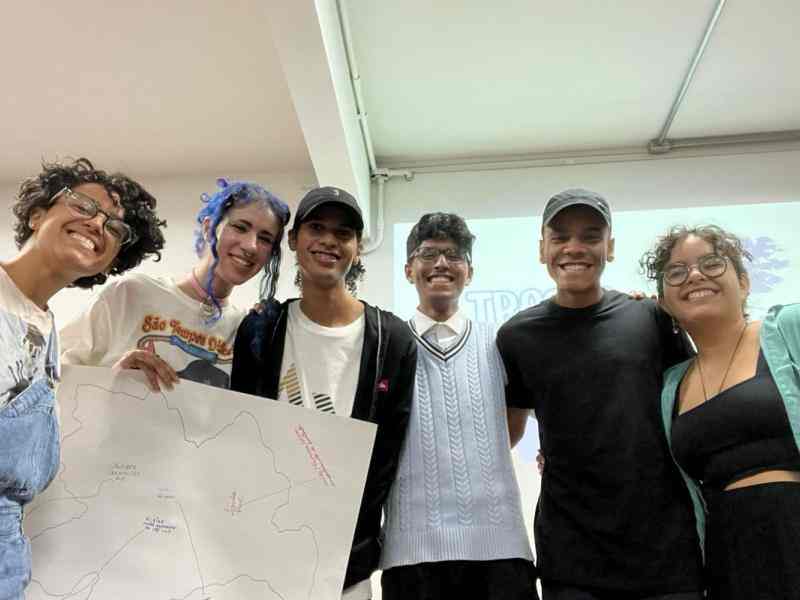 Diversas pessoas sorrindo segurando um cartaz