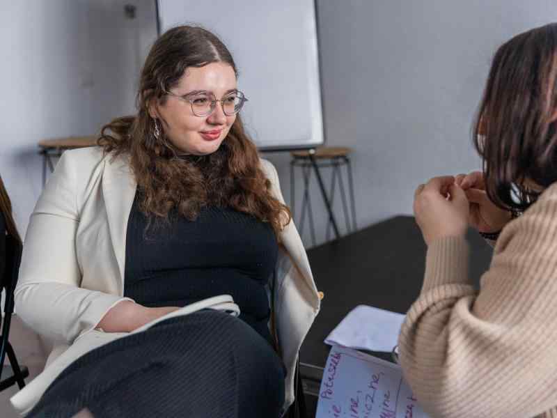 Two young woman sitting facing each other and talking