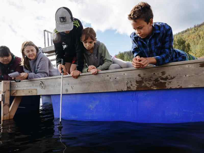 Group of youth as well as some parents monitoring water data off the side of a dock