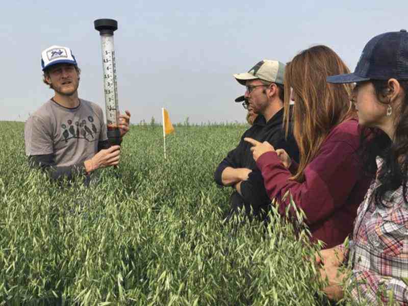 Jason Stuka with a group of young farmers teaching in a farm field