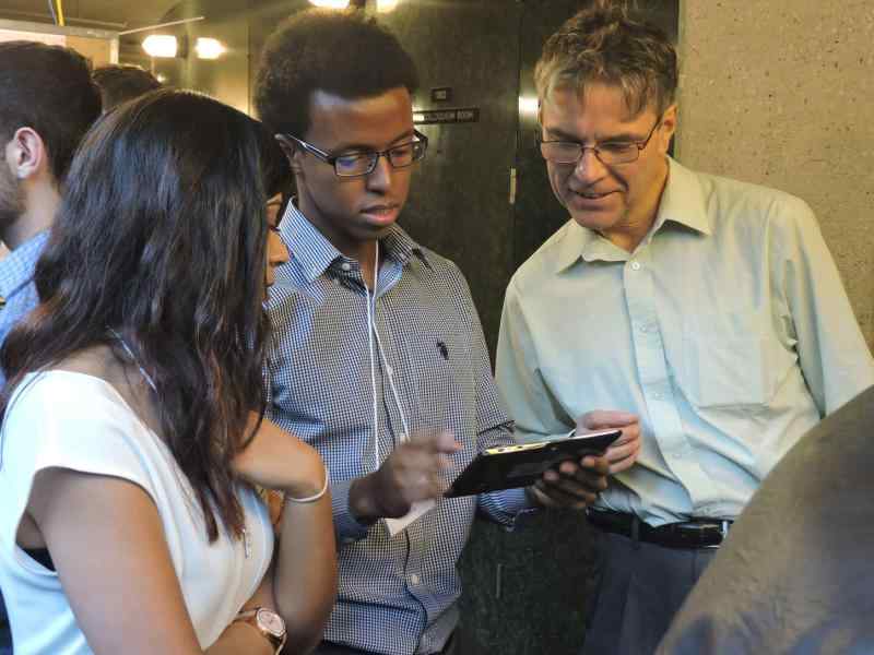 Brett Matthews looking at an ipad with two other people in a conference room