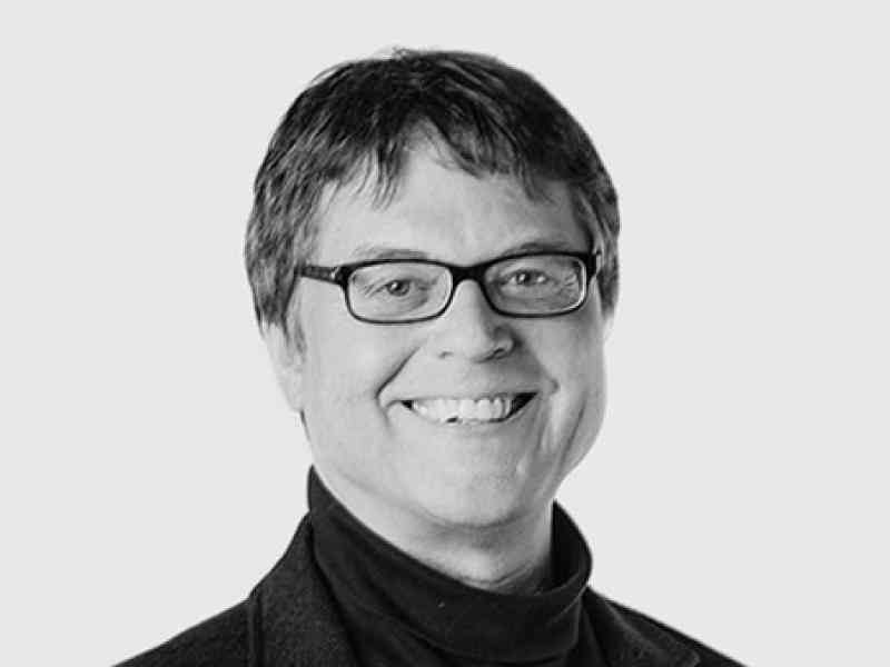Black and white headshot of Canada Fellow Brent Kopperson. Person with short hair and glasses smiling at the camera
