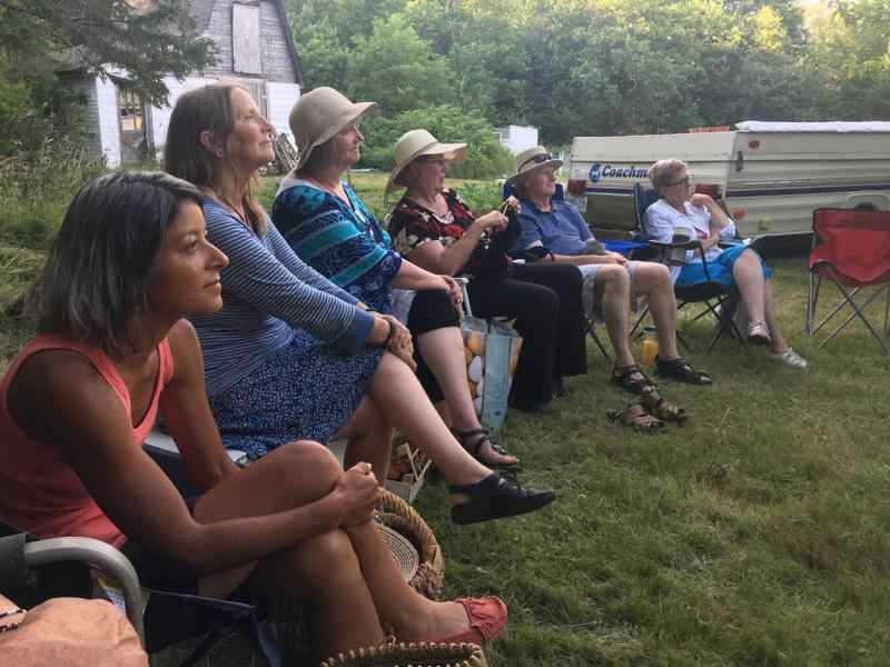 Group of people in a field paying attention to a Life.School.House session