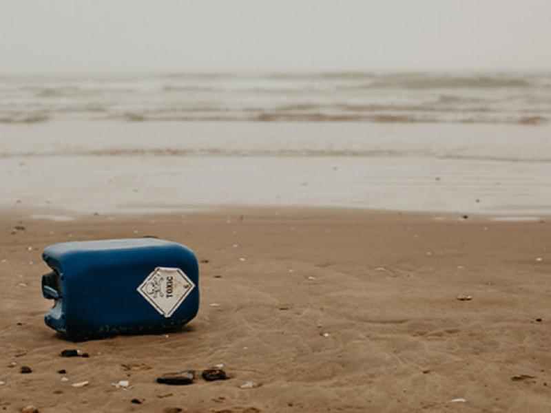 Image of a can of oil knocked over on a beach