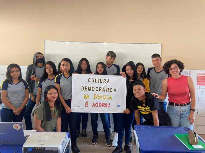 Grupo de jovens seguram cartazes sobre cultura democrática