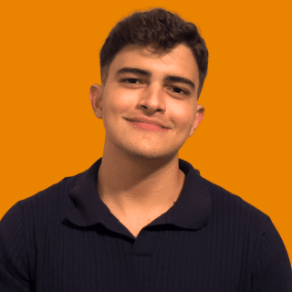 Pablo é um jovem branco de cabelos curtos. Ele usa uma camisa polo preta e dá um leve sorriso para a foto