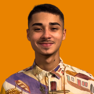 Samuel é um jovem com bigode e cabelos curtos. Ele veste uma camisa estampada e dá um leve sorriso para a foto