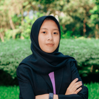 Headshot of a girl smiling at the camera on a nature background.