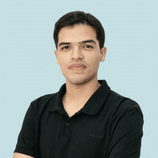 Igor é um jovem branco de cabelos curtos e escuros. Ele veste uma camisa polo preta e olha para a câmera